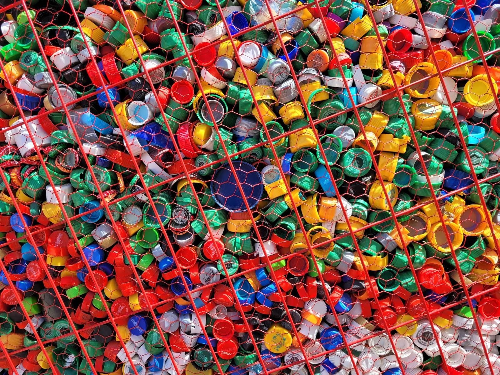 A large number of assorted colored plastic bottle caps in a wire mesh container bound for recycling in Chile