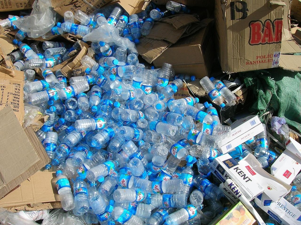 Countless used clear plastic water bottles with labels and caps on together with plastic bags,  cardboard, paper, and other materials 