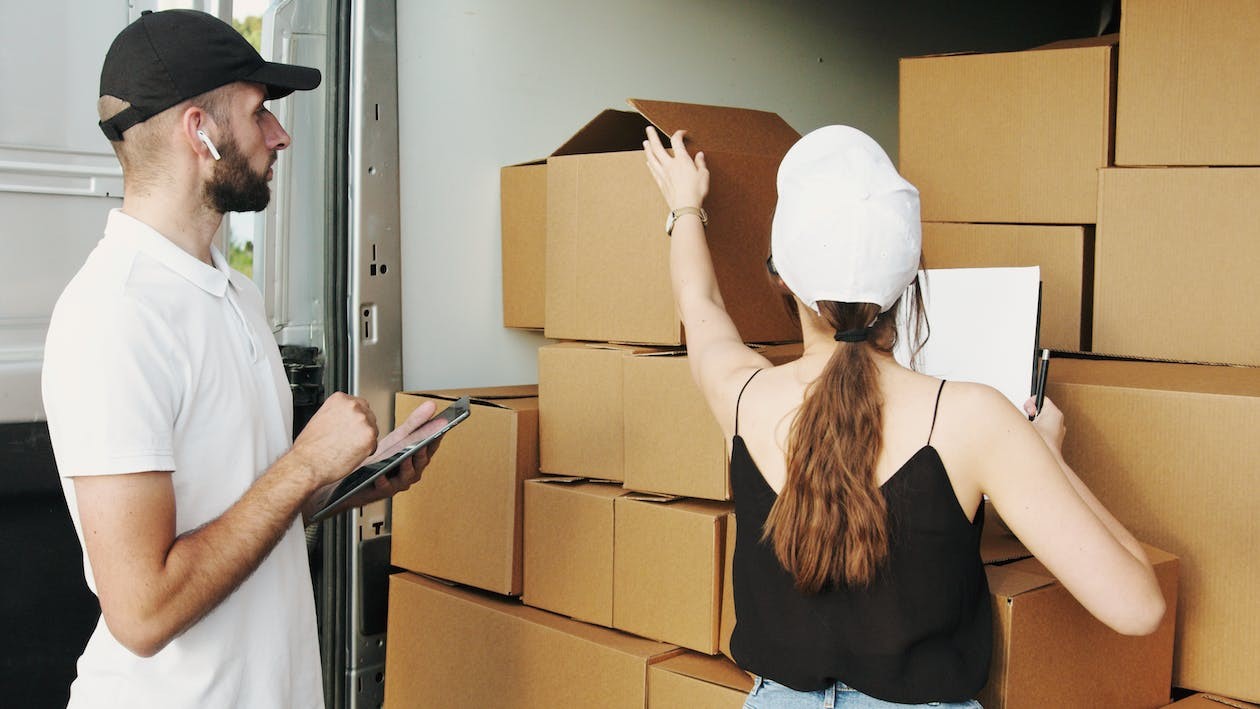 two workers in a delivery truck organizing cardboard boxes for shipping