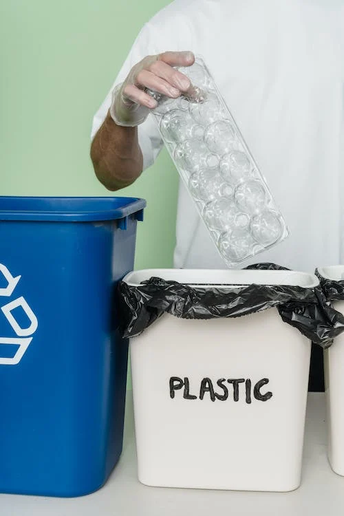 Person sorting plastic waste into a designated recycling bin.